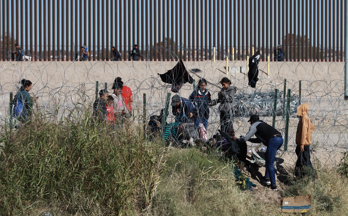Migrantes cerca del muro fronterizo. (EFE)