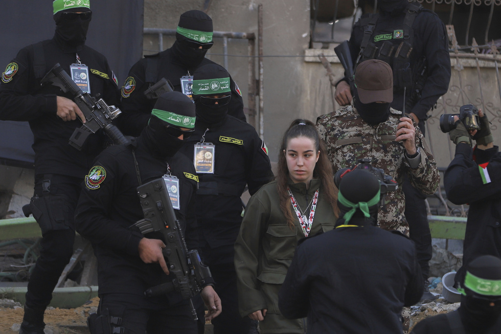 La soldado israelí Agam Berger camina junto a milicianos enmascarados de Yihad Islámica | AP