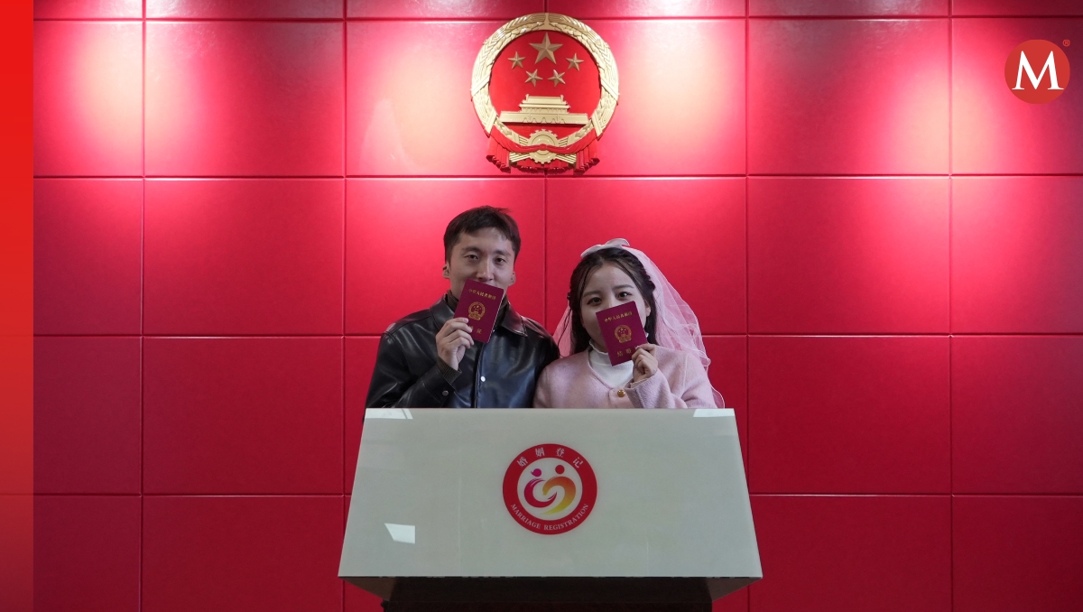 Los recién casados ​​Xue Zhenkai  y Liu Cuifang posan con sus libros de matrimonio en una oficina administrativa en Luliang. | AFP