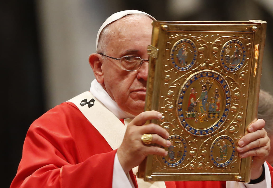 El Papa Francisco levanta el libro del Evangelio durante una misa en la que entregó el Palio en 2014. | AFP