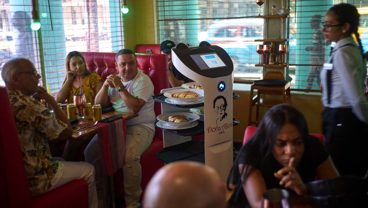 Clientes observan cómo un robot llega con su comida al restaurante "Doña Alicia" en La Habana. (Foto: AP)