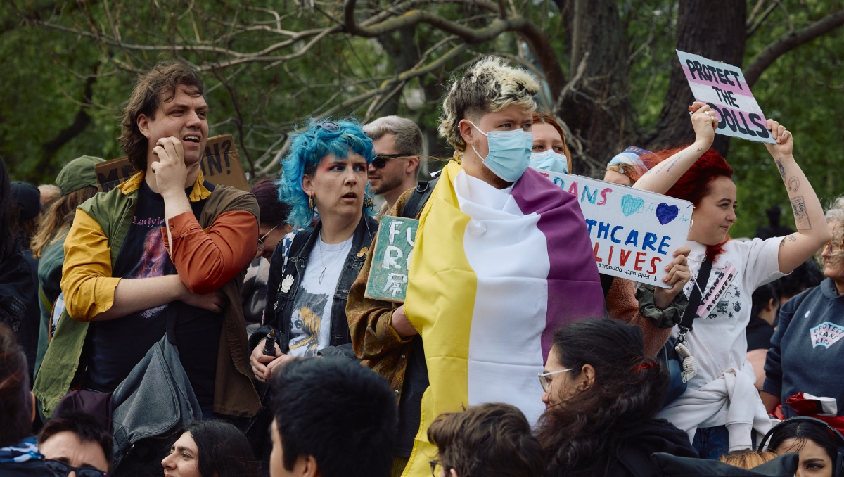Manifestantes ondean banderas y portan pancartas junto al Parlamento británico en apoyo a los "derechos trans". | AFP