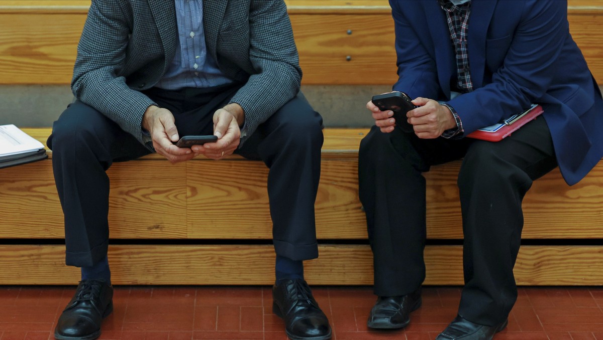 Personas mirando ofertas de trabajo en sus móviles durante una feria laboral. Mayo 2021. Foto: Reuters