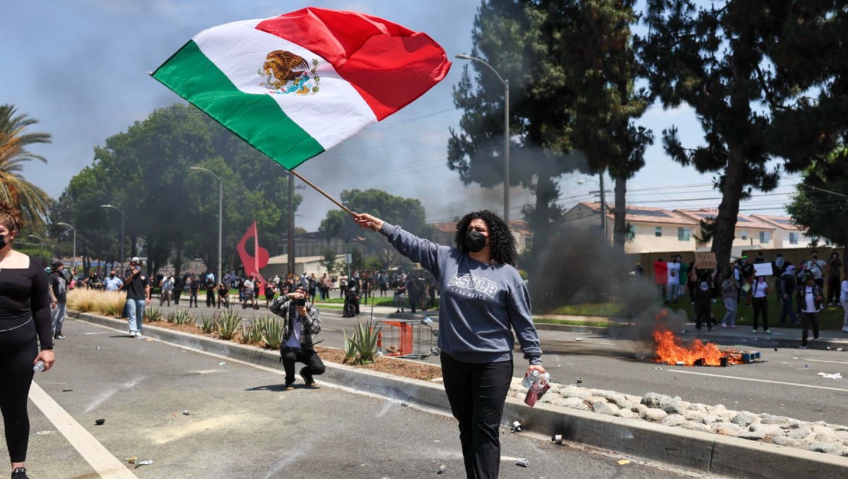 Manifestante sosteniendo una bandera mexicana durante una protesta contra las redadas migrantes: Los Ángeles. | EFE