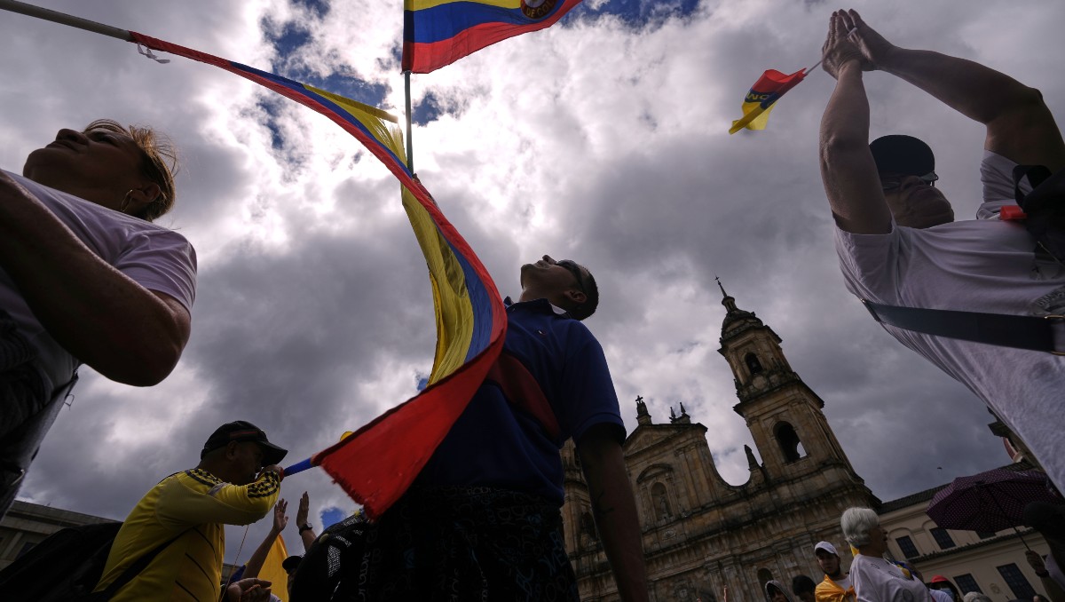 Manifestantes ondean banderas de Colombia para condenar el intento de asesinato contra el senador opositor Miguel Uribe Turbay. AP