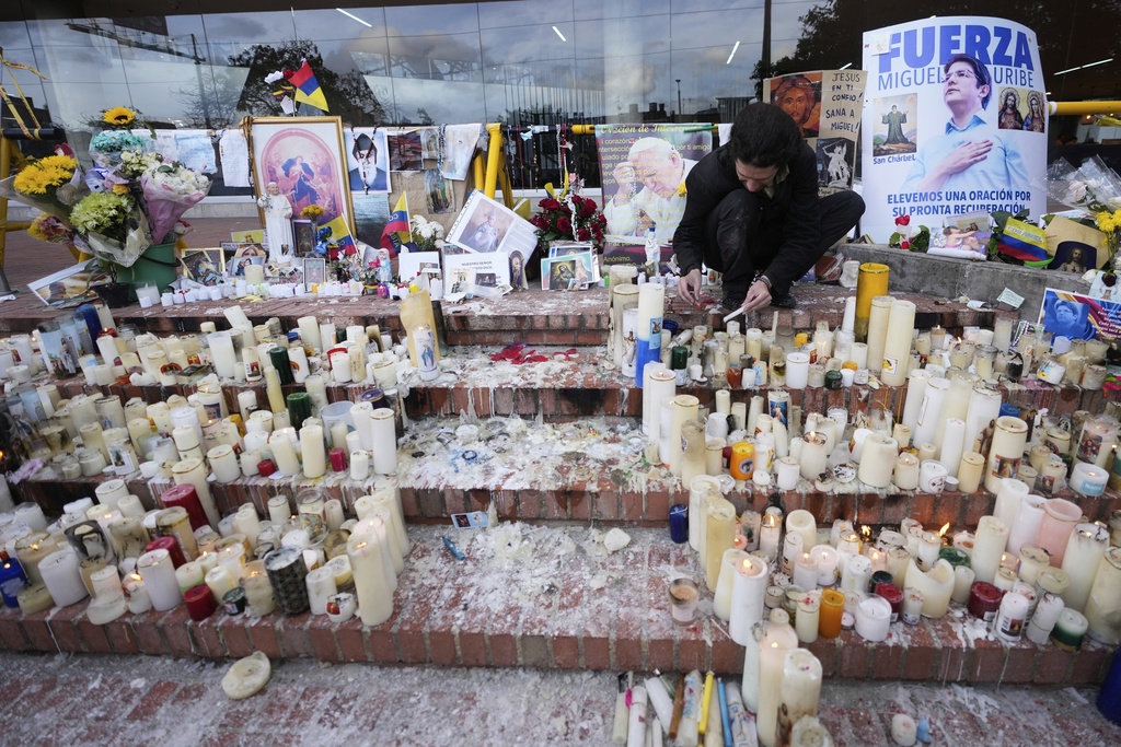 Un hombre enciende velas en un altar que se instaló en honor al senador colombiano Miguel Uribe Turbay. | AP