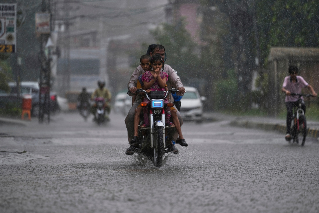 Un motociclista y su familia conducen por una calle durante una fuerte lluvia en Rawalpindi, Pakistán. AP
