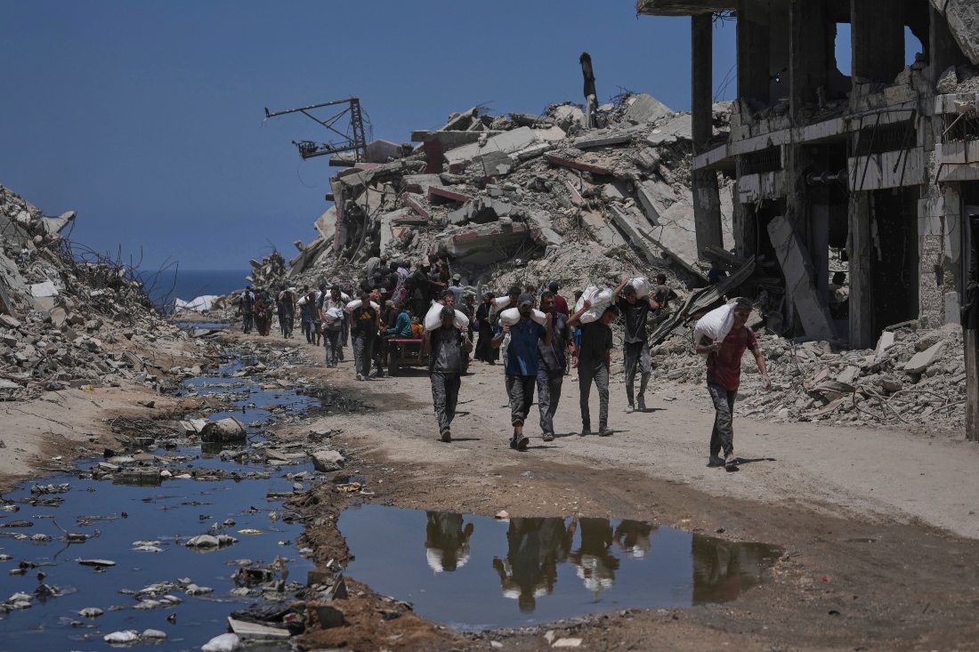 Palestinos cargan bolsas de harina que descargaron de un convoy de ayuda humanitaria que llevó en la Ciudad de Gaza. |AP