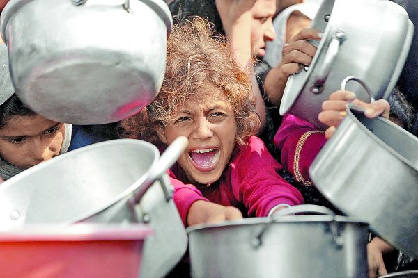 Un niño extiende una olla mientras clama por comida en una cocina ambulante en Jan Yunis. Reuters