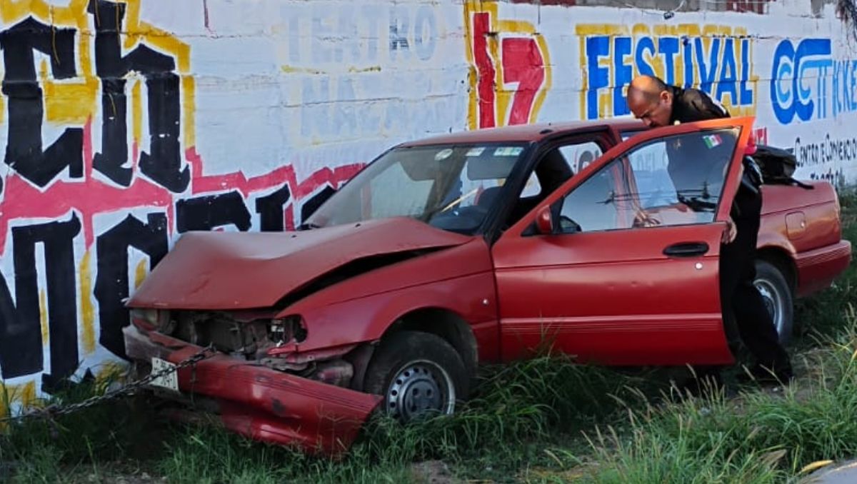 El vehículo Nissan Tsuru en color rojo quedó detenido en un área de terracería después del choque. | Especial
