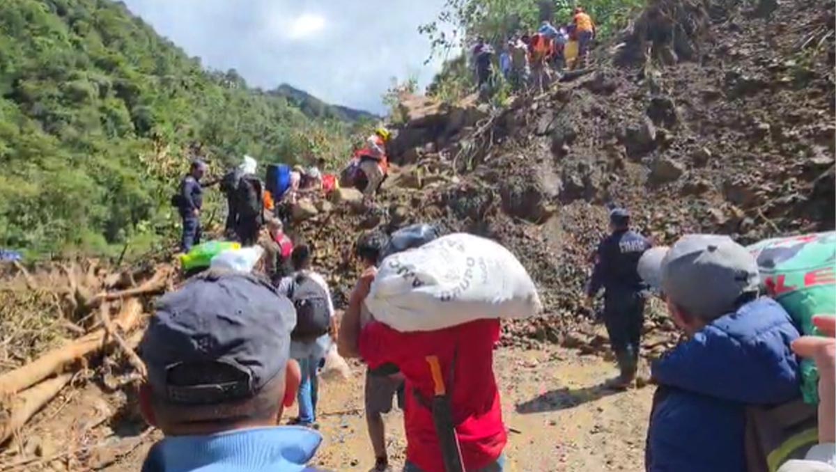 Habitantes cruzan a pie el tramo bloqueado de la carretera Tenango–Huehuetla para llevar víveres.