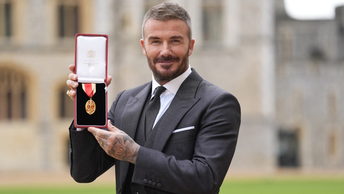 El exfutbolista inglés David Beckham posa con su medalla tras ser nombrado Caballero por sus servicios al deporte y a la beneficencia | AFP