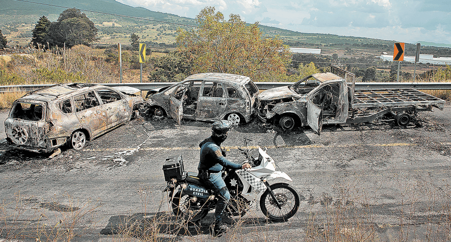 Un oficial patrulla sobre la autopista al municipio de Quiroga, donde quedaron tres unidades calcinadas. AFP