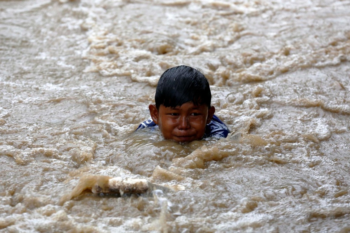 Un niño nada en un charco de agua en una aldea afectada por las inundaciones en Indonesia este martes. | Agencia EFE