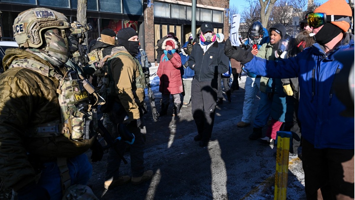 Agentes federales observan mientras los manifestantes se reúnen cerca del lugar donde un hombre fue baleado | AFP