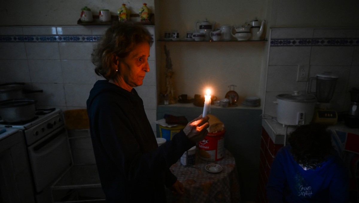 Mujer sostiene una vela mientras durante un apagón en el barrio de Luyano, La Habana. | AFP