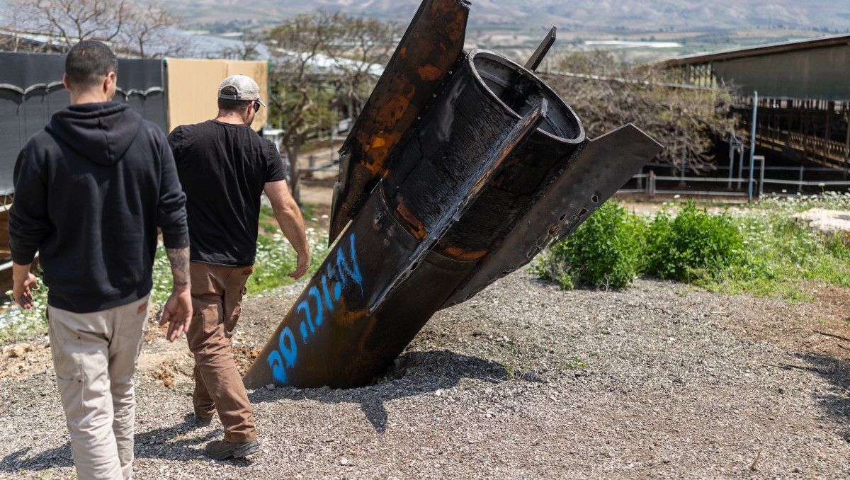Ciudadanos israelís contemplando los restos de un misil iraní. | AFP