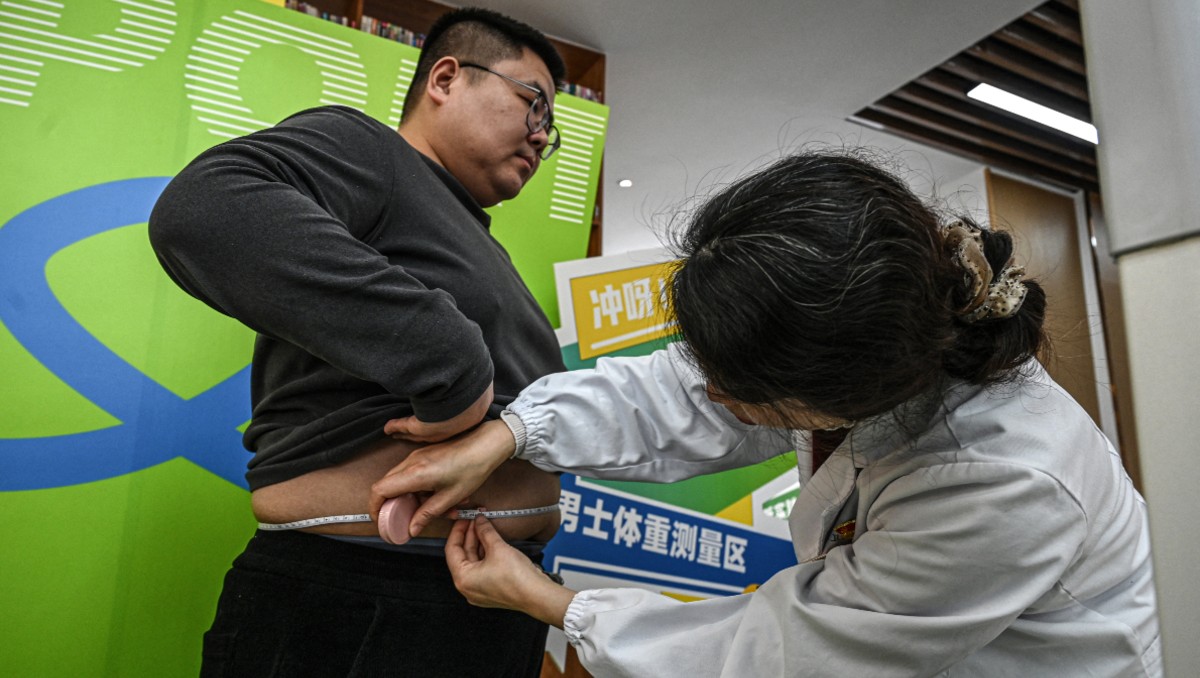 Un participante se somete a una medición de cintura en un centro comunitario local en Wuxi, al este de China. | AFP