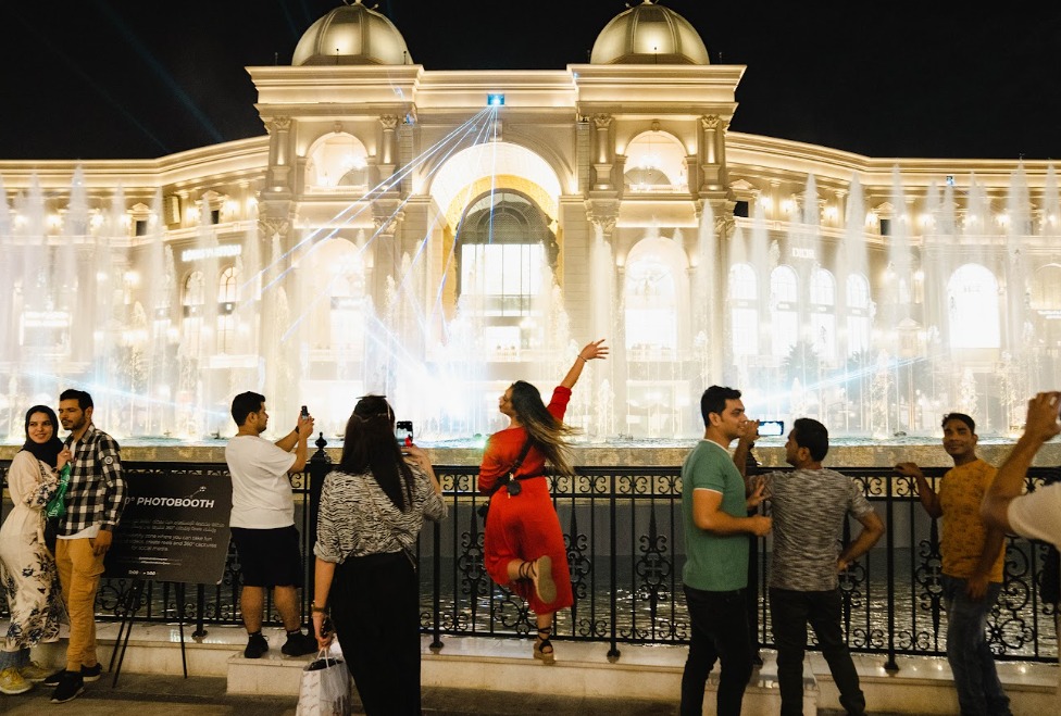 Personas toman fotografías durante un espectáculo de luces y agua en el centro comercial Place Vendome en Lusail, Catar, en 2022. | Foto: Erin Schaff