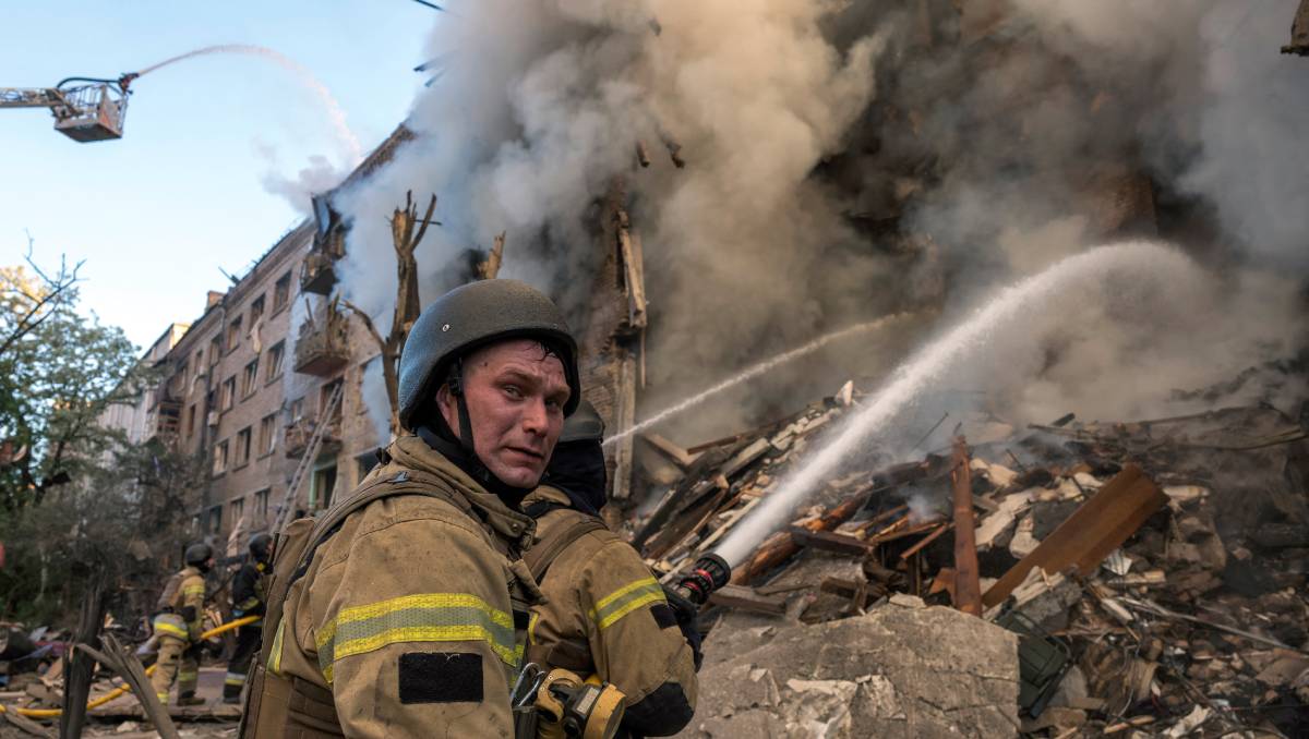 Bomberos trabajan para extinguir un incendio en un edificio dañado tras los ataques rusos a la capital ucraniana. | AFP
