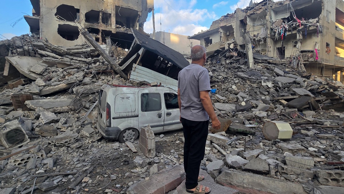 Hombre busca sus pertenencias entre los escombros de un edificio destruido en la ciudad costera de Tiro. | AFP