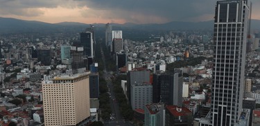 Horizonte de Ciudad de México en una puesta de sol mientras los autos se muestran a lo largo de avenida Reforma.
