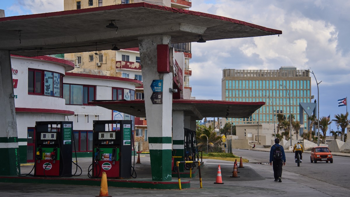 Un hombre pasa junto a una gasolinera sin combustible, ubicada cerca de la Embajada de Estados Unidos, que se ve al fondo, en La Habana, Cuba. | AP