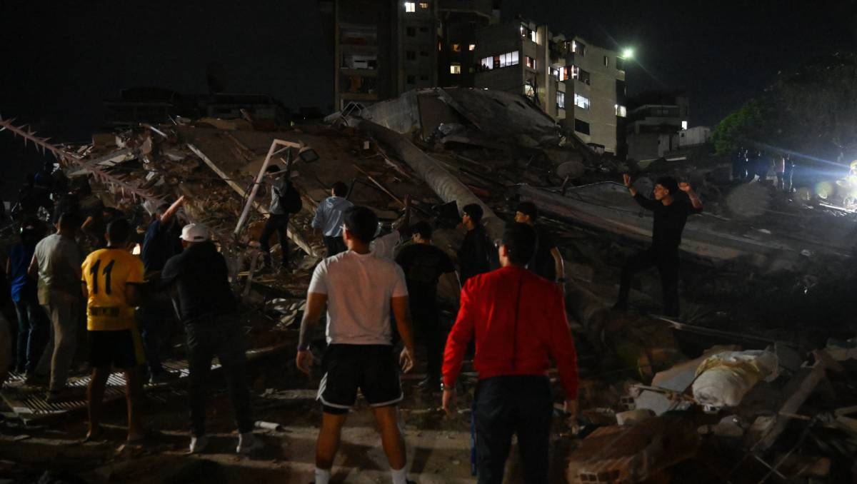 Gente está junto a un edificio derrumbado después de un terremoto en Caracas. | Foto: AFP