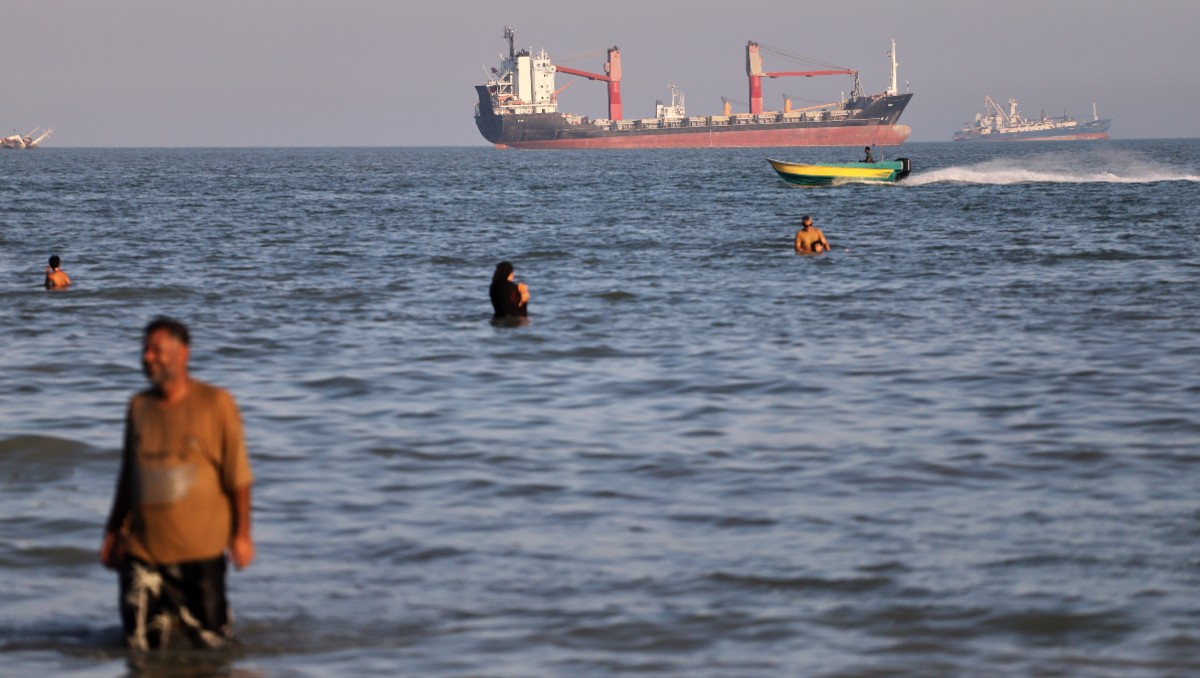 Buques Comerciales y cargueros circulan día a día por el estrecho de Ormuz mientras turistas nadan en sus aguas. | AP