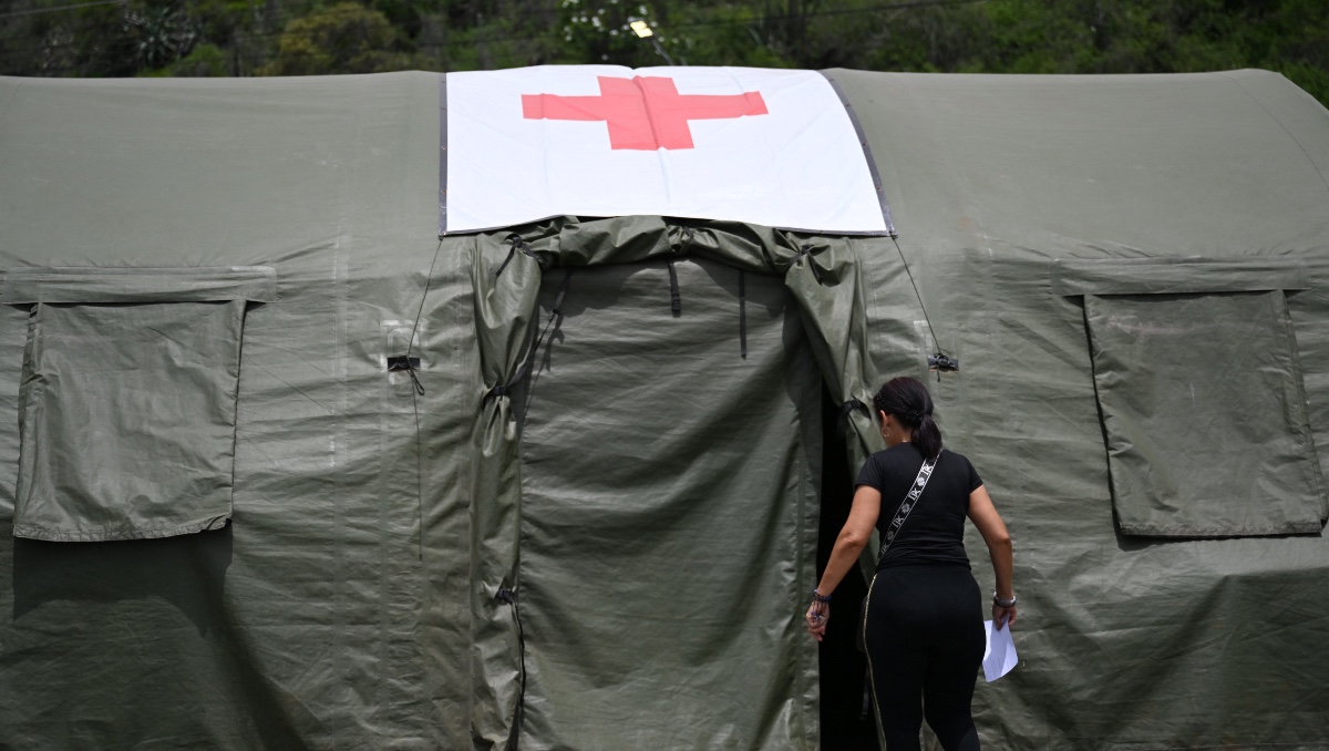 Mujer entra en una tienda de campaña del hospital de campaña militar de Brasil en Camuri Chico, cerca de Macuto, en el estado de La Guaira. | AFP