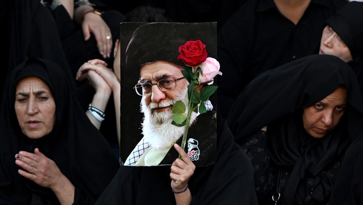 Mujer sostiene flores y un retrato del asesinado líder supremo de Irán, Alí Jameneí. | AFP