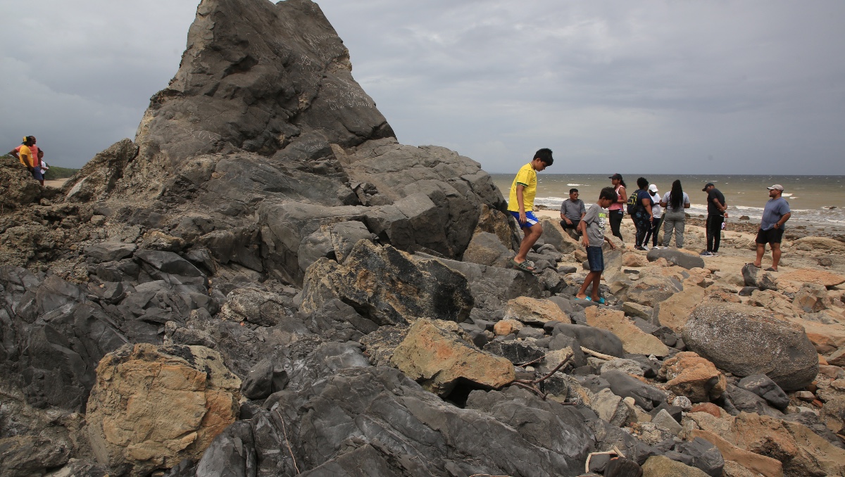 Niños caminando sobre una roca que alguna vez estuvo sumergida y que ahora forma parte de la nueva línea costera de Galfa en Cedros. | EFE