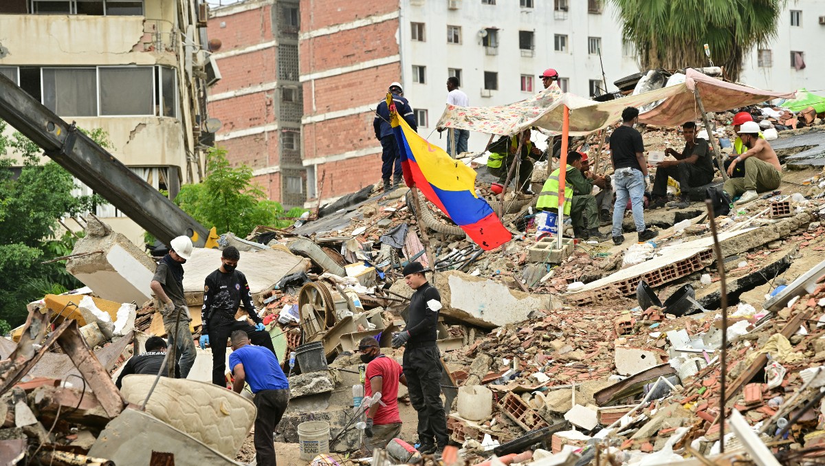 Equipos de rescate y familiares de personas desaparecidas buscan cuerpos entre los escombros de un edificio colapsado en Caraballeda, La Guaira. | AFP