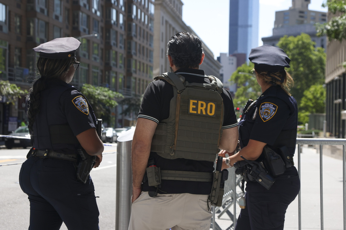 Agentes de policía y un oficial de Operaciones del ICE custodian la escena del crimen. | EFE