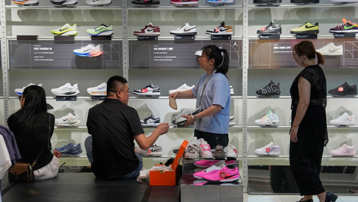 Un trabajador atiende a un cliente mientras la gente compra en una tienda de ropa deportiva Nike en Pekín, China. Julio de 2026. | Foto: AP