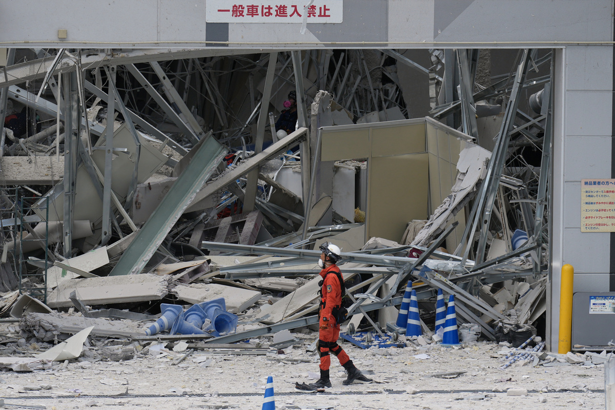 Rescatista camina frente al centro comercial AEON, el cual resultó dañado por una explosión luego de un sismo. | AP