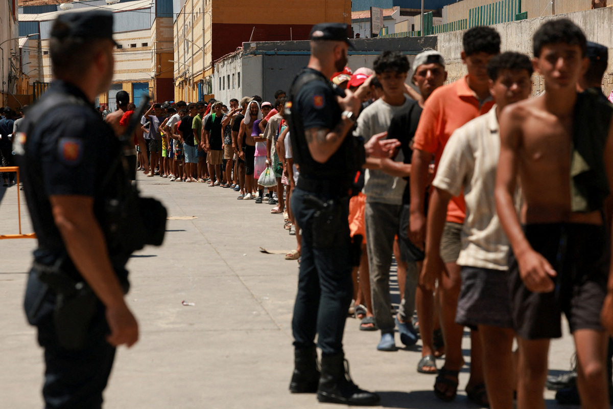 Migrantes hacen fila para recibir alimentos básicos de la ONG local Media Luna Blanca en una zona industrial donde pernoctan. | Reuters