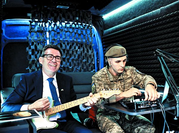 El premier británico, Andy Burnham, toca la guitarra en una unidad militar. REUTERS