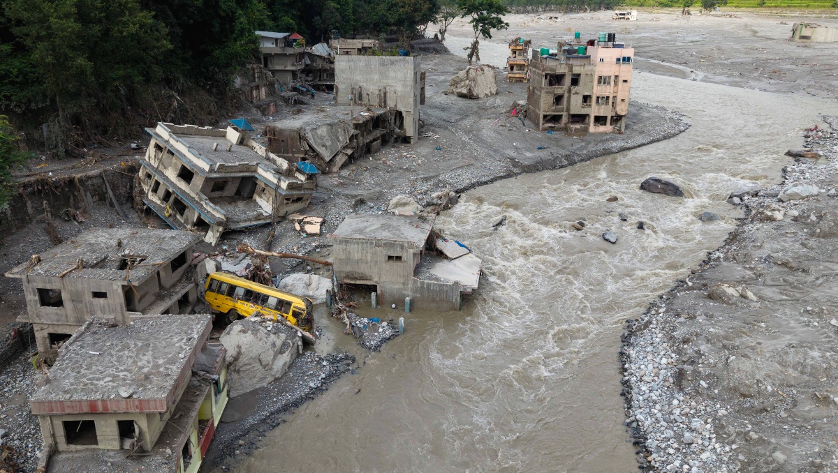 Torrente de agua fangosa que avanza con fuerza junto a las viviendas y a través del río Trishuli tras unas inundaciones. | AFP