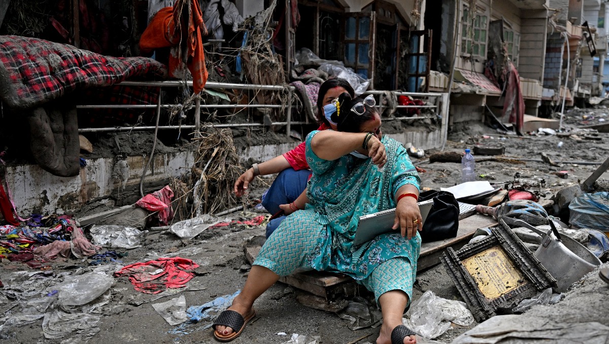 Personas rescatan sus pertenencias de sus hogares tras unas inundaciones repentinas en Devighat, en el distrito nepalí de Nuwakot. | AFP