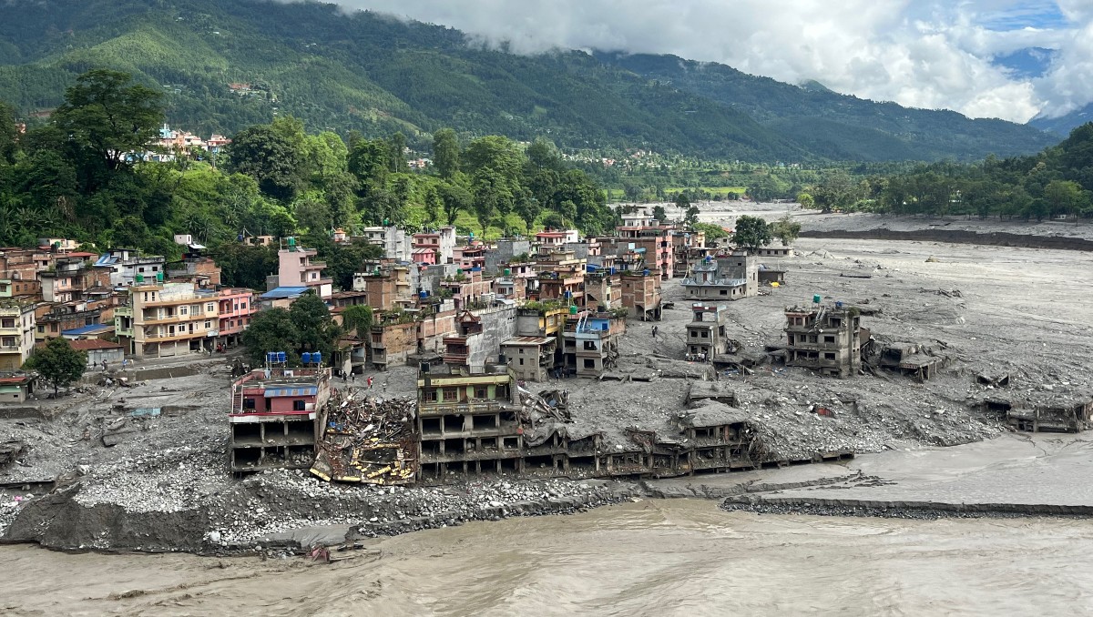 orrente de agua fangosa que avanza con fuerza junto a las viviendas y a través del río Trishuli,