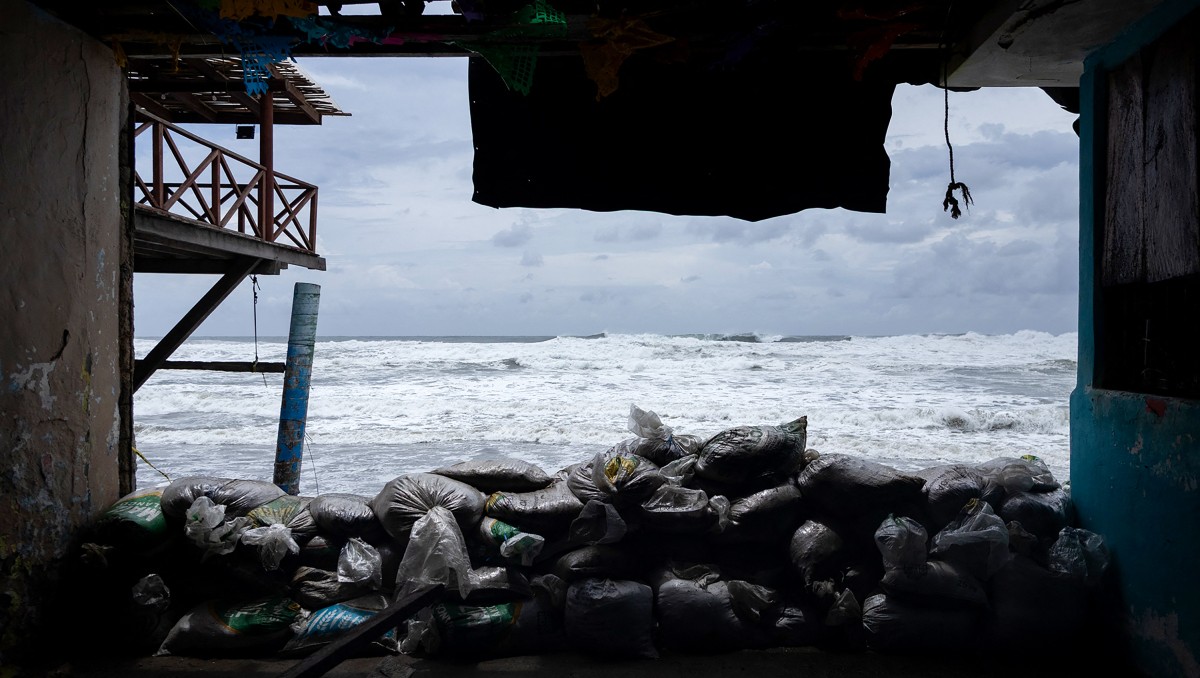 Vista de sacos de arena como barrera de protección contra el fuerte oleaje generado por el huracán Polo en Playa Azul, Lázaro Cárdenas. | AFP
