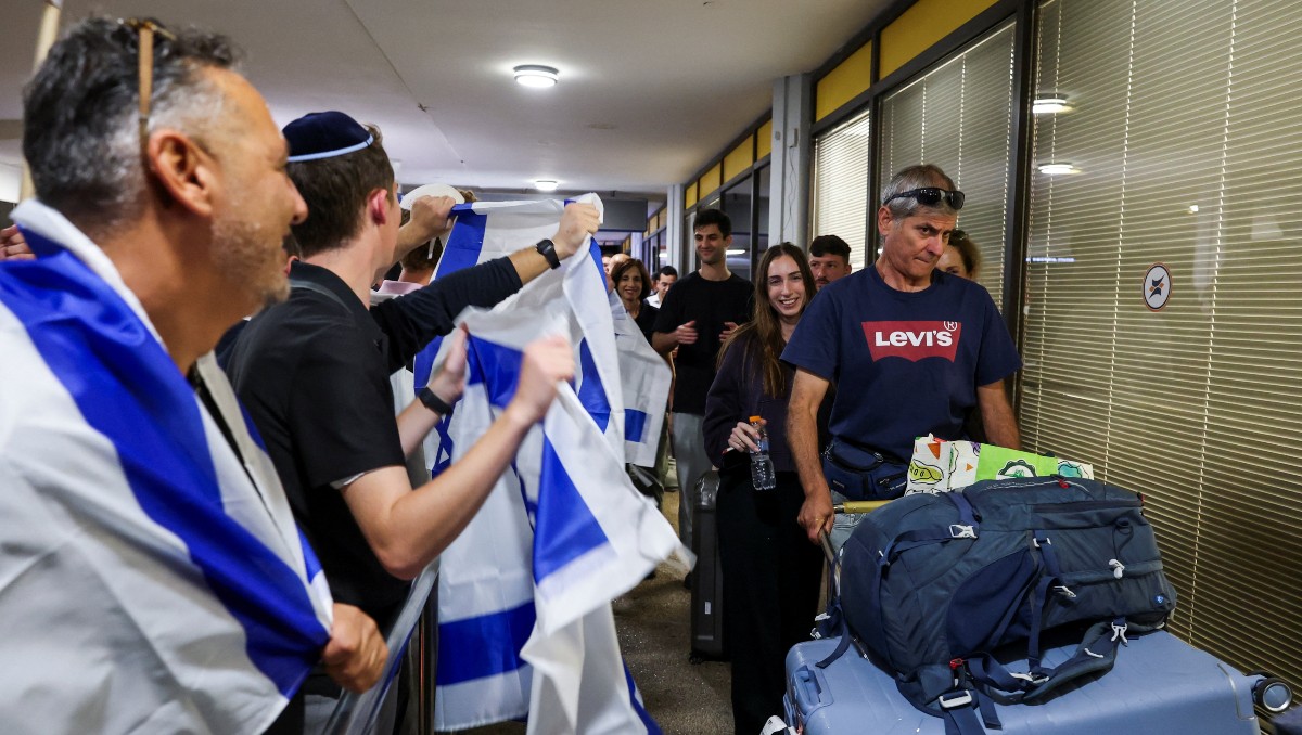 Personas envueltas en banderas israelíes saludan a los pasajeros del avión de FlyDubai | Foto: Reuters