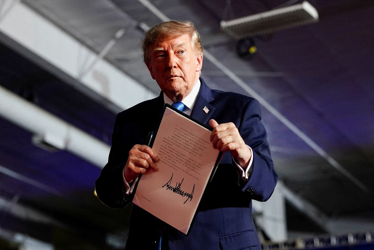 El presidente de Estados Unidos, Donald Trump, sostiene una orden ejecutiva tras firmarla en el escenario durante un mitin. | Reuters