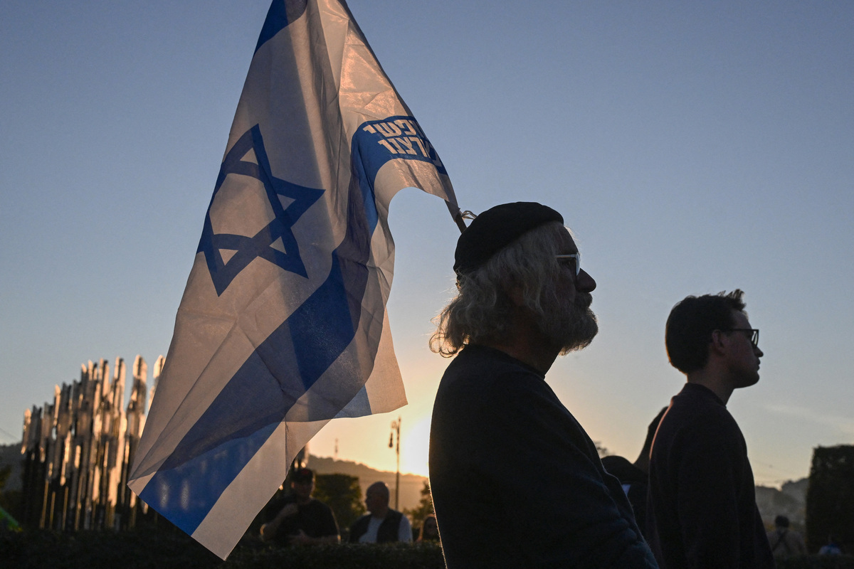Personas con banderas de Israel asisten a una ceremonia de conmemoración de las víctimas del ataque de Hamás del 7 de octubre. | AFP