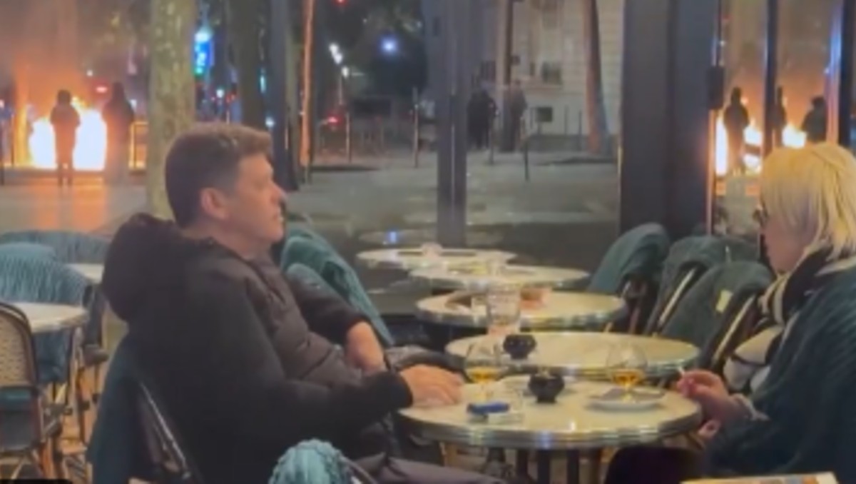 Pareja disfruta de sus bebidas durante protestas en París. | Redes sociales